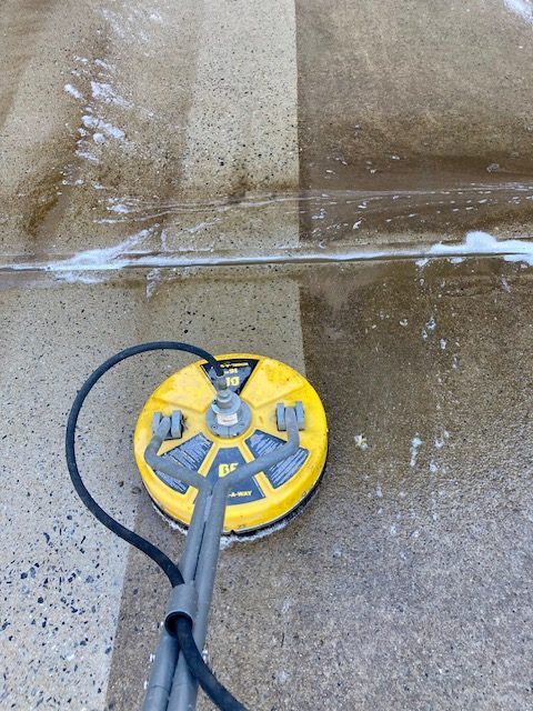 A surface cleaner attachment cleaning a concrete driveway